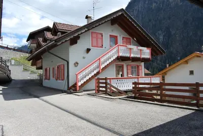 a white house with red windows and a fence at Appartamento Col Val di Fassa con Terrazza BAGNI RINNOVATI 2023 in Campitello di Fassa