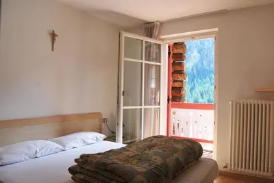 a bedroom with a bed and a window with a cross at Appartamento Col Val di Fassa con Terrazza BAGNI RINNOVATI 2023 in Campitello di Fassa