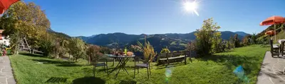 a table and chairs on a lawn with mountains in the background at Ferienbauernhof Wieserhof in Fiè