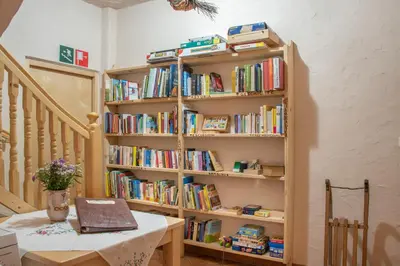 a book shelf filled with books next to a table at Ferienbauernhof Wieserhof in Fiè