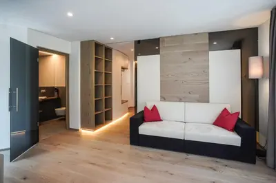 a living room with a white couch with red pillows at Gasthof Sonne snc in Sarntal