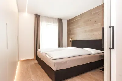 a bedroom with a large bed with a wooden wall at Gasthof Sonne snc in Sarntal