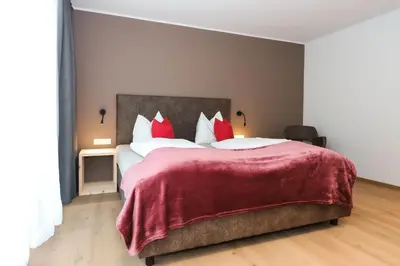 a bedroom with a large bed with red pillows at Gasthof Sonne snc in Sarntal
