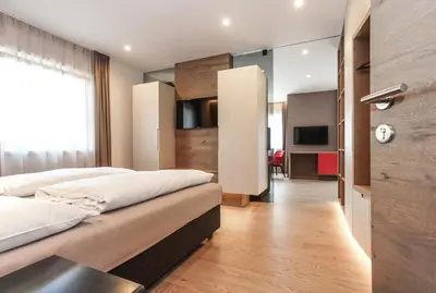 a bedroom with two beds and a living room at Gasthof Sonne snc in Sarntal