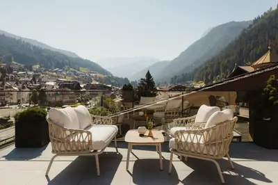 a balcony with chairs and a view of a town at Hotel COSMEA 4 Stars - Your Dolomites experience in Ortisei