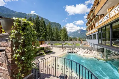 a house with a infinity pool with a mountain view at Croce Bianca Leisure & Spa Hotel in Canazei