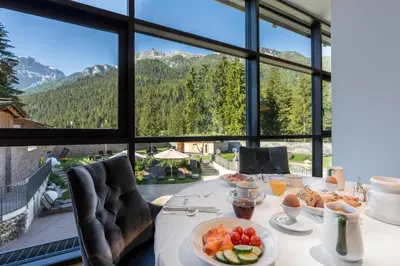 a view of a hotel with a swimming pool and mountains at Croce Bianca Leisure & Spa Hotel in Canazei