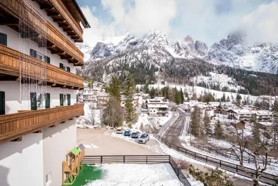 a view from a balcony of a resort with snow covered mountains at Hotel Colfosco in San Martino di Castrozza