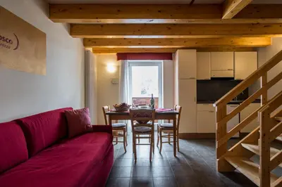 a living room with a red couch and a table at Hotel Colfosco in San Martino di Castrozza