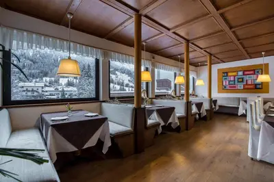 a restaurant with tables and chairs and large windows at Hotel Colfosco in San Martino di Castrozza