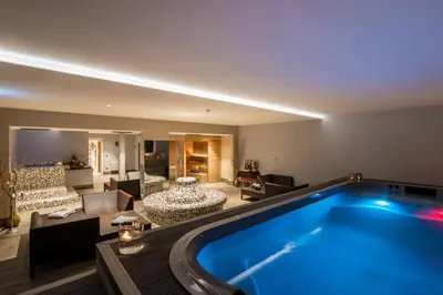 a large swimming pool in a living room at Hotel Colfosco in San Martino di Castrozza