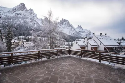 a balcony with snow covered mountains in the background at Hotel Colfosco in San Martino di Castrozza