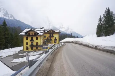 a building on the side of a road with snow at GH Hotel Fratazza in San Martino di Castrozza