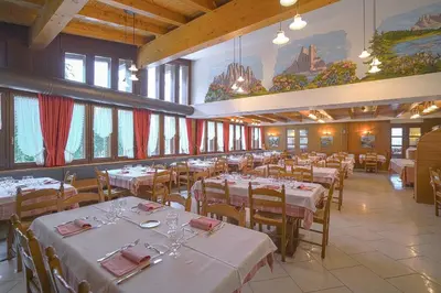 a dining room with white tables and chairs and windows at GH Hotel Fratazza in San Martino di Castrozza