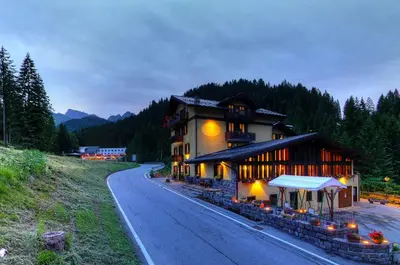 a large building on a road next to a mountain at GH Hotel Fratazza in San Martino di Castrozza