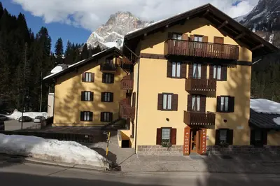 a yellow building with a balcony and a mountain at GH Hotel Fratazza in San Martino di Castrozza
