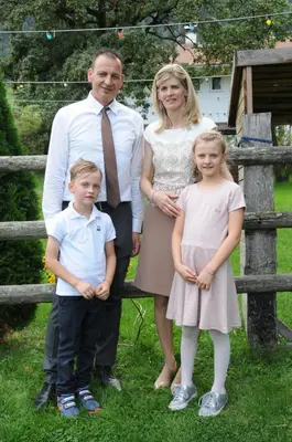 a family posing for a picture in front of a fence at Hotel Sigmunderhof in Chienes