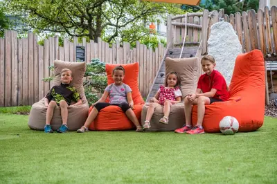 three children sitting on bean bags on a playground at Hotel Sigmunderhof in Chienes