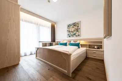 a bedroom with a large white bed with blue pillows at Hotel Sigmunderhof in Chienes