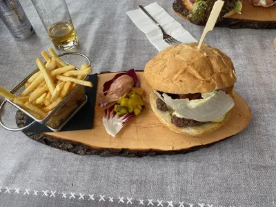 a hamburger and french fries on a wooden board at NRH Laurin Karersee in Nova Levante