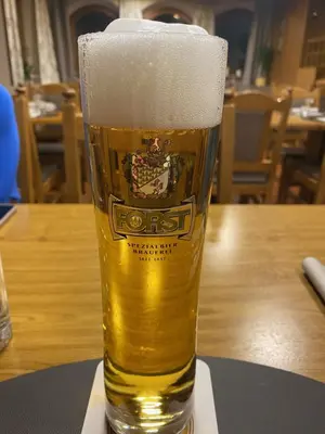 a glass of beer sitting on a table at NRH Laurin Karersee in Nova Levante