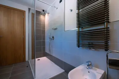 a bathroom with a sink and a glass shower at HOTEL B&B MARILENA in Arabba