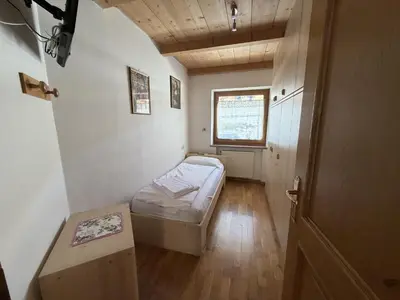 a small room with a bed and a window at Appartamento Star Begn - Mansarda in Soraga