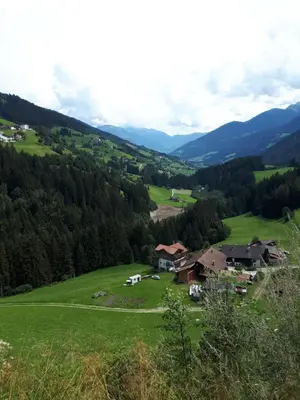 a farm in a green field with mountains in the background at Ober-Gruberhof in Ridanna