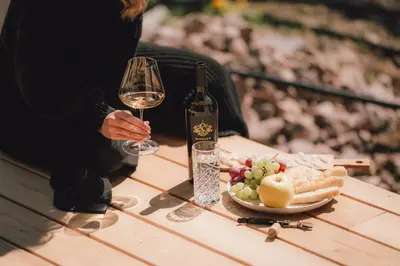 a person holding a glass of wine and a plate of food at Pitzner - Winery & Suites in Cornedo all'Isarco