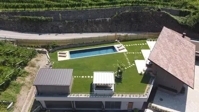 an aerial view of a house with a yard with a swimming pool at Pitzner - Winery & Suites in Cornedo all'Isarco