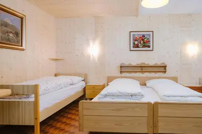 two twin beds in a room with two tables at Garni Fany in Colfosco