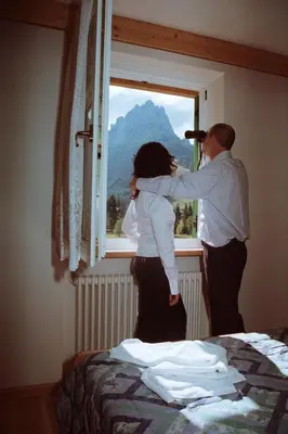 a man and a woman looking out of a window at Residence Holiday in Pozza di Fassa