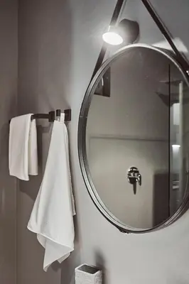 a bathroom with a round mirror and white towels at Stufels 7 Design Apartment with Brixen Card in Bressanone