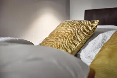 a bed with a gold pillow on top of it at Stufels 7 Design Apartment with Brixen Card in Bressanone