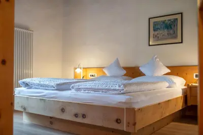 a bedroom with a wooden bed with white sheets and pillows at B&B Unterhabsbergerhof in Appiano sulla Strada del Vino