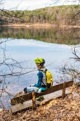 a person sitting on a bench next to a lake at B&B Unterhabsbergerhof in Appiano sulla Strada del Vino