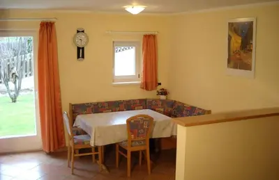 a dining room with a table and a couch at Appartments Am Wiesenrand in Nova Ponente