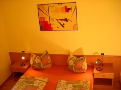 a bedroom with two beds and a clock on the wall at Appartments Am Wiesenrand in Nova Ponente