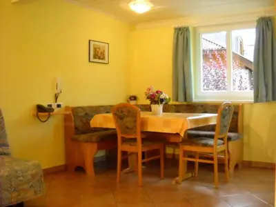 a dining room with a table and chairs and a window at Appartments Am Wiesenrand in Nova Ponente