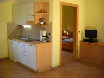 a kitchen with a sink and a room with a bed at Appartments Am Wiesenrand in Nova Ponente