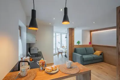 a kitchen and living room with a table and a couch at Cesa La Doe Majons in Campitello di Fassa