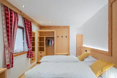 two beds in a small bedroom with red curtains at Cesa La Doe Majons in Campitello di Fassa