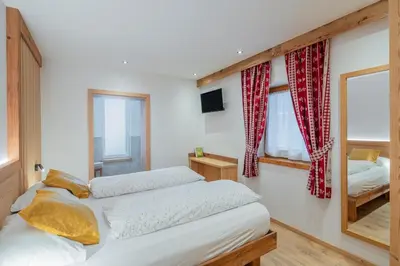 a bedroom with two beds and a mirror at Cesa La Doe Majons in Campitello di Fassa