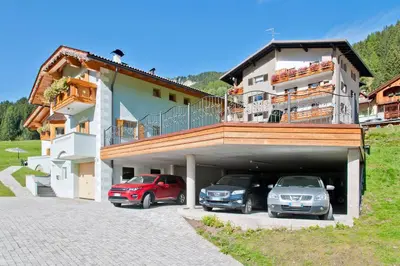 a building with two cars parked in a garage at Cesa La Doe Majons in Campitello di Fassa