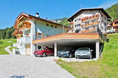 a building with two cars parked in a garage at Cesa La Doe Majons in Campitello di Fassa
