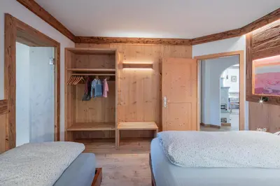 a bedroom with a bed and a wooden wall at Cesa La Doe Majons in Campitello di Fassa