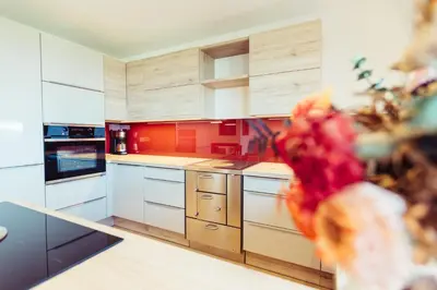 a large kitchen with white cabinets and red accents at Ferienwohnung Pension Stern in Aldino