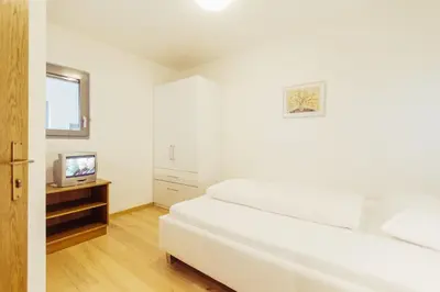 a white bedroom with a white bed and a television at Ferienwohnung Pension Stern in Aldino