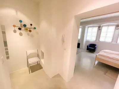 a white room with a bed and a chair at Lauben Suite Old Town Bolzano in Bolzano