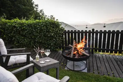 a fire pit on a deck with a table and chairs at Pippos Mountain Lodge in Soprabolzano